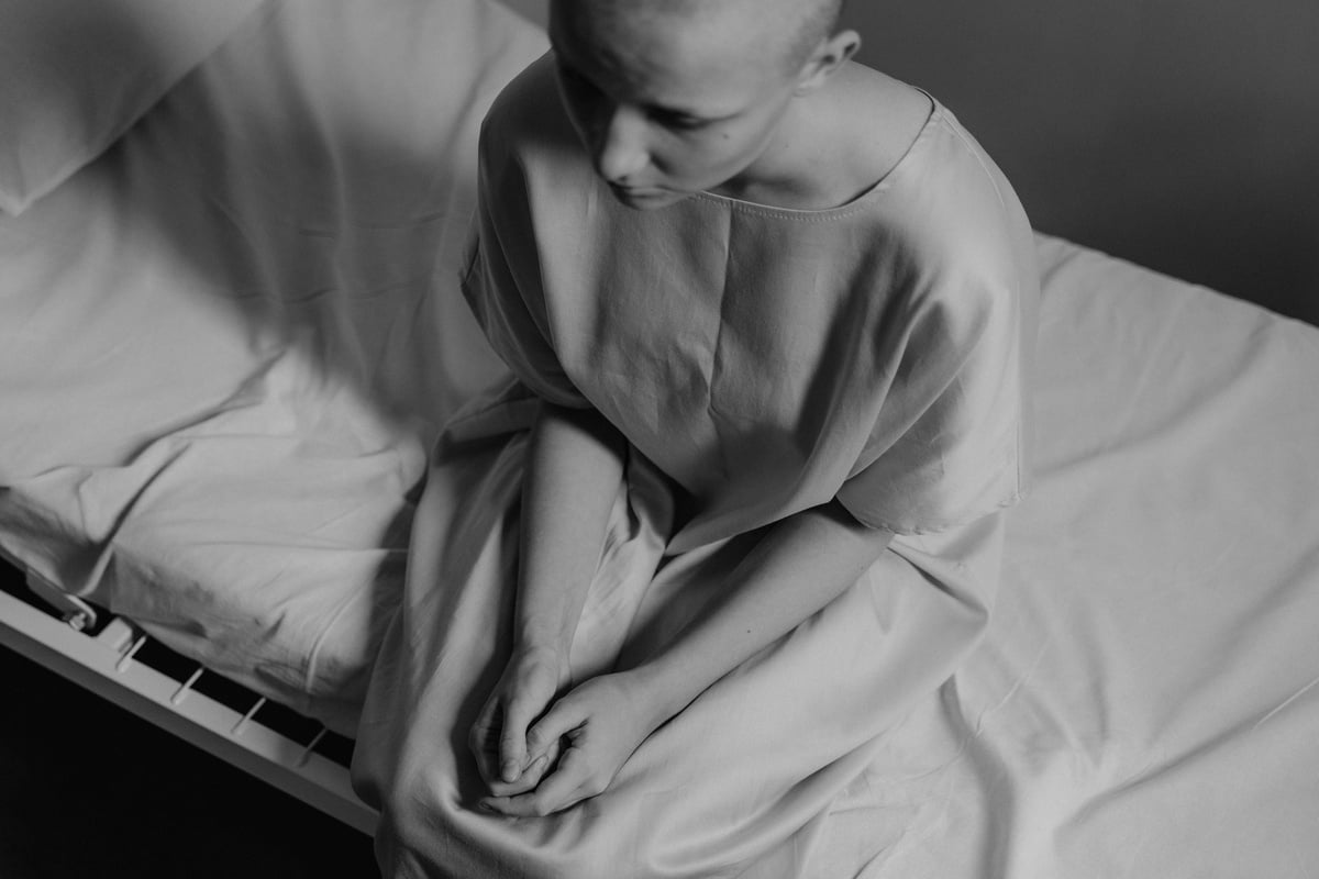 Grayscale Photo of a Patient Sitting on Hospital Bed